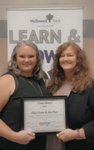 Two women pose with a certificate.